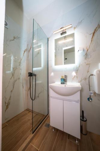 a bathroom with a sink and a glass shower at Penelope - Sea Front Studio in Gouvia