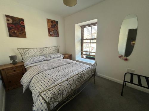 a bedroom with a bed and a mirror and a window at New Drovers in Llanelli