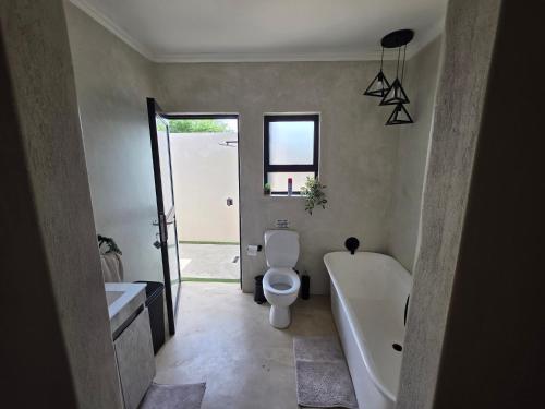 a bathroom with a toilet and a tub and a sink at Taíta Lodge in Marloth Park