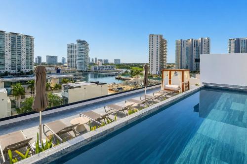 a swimming pool with chairs and a view of a city at Luxury Retreat in Puerto Cancun with Rooftop Pool in Cancún