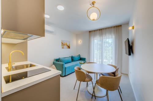 a kitchen and living room with a table and a blue couch at 7 Olives Luxury Suites in Rogoznica