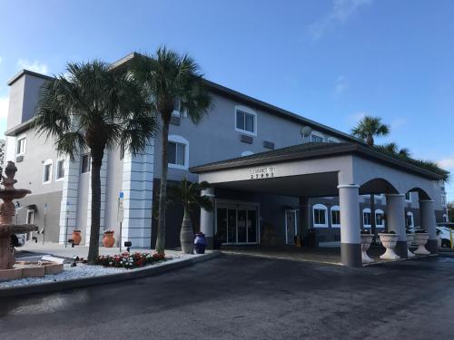 a hotel with palm trees in front of a building at Days Inn & Suites by Wyndham Bonita Springs North Naples in Bonita Springs