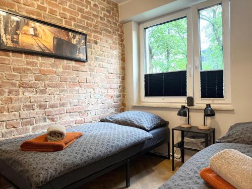a bedroom with two beds and a brick wall at Apartament Kopalniok II in Zabrze