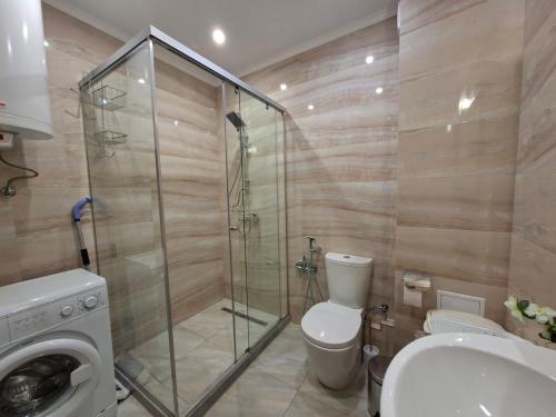 a bathroom with a toilet and a glass shower stall at Argisht complex apart 208 in Golden Sands