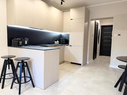 a kitchen with a black and white counter and stools at Apartament Kopalniok II in Zabrze