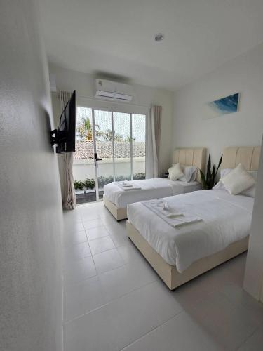 a bedroom with two beds and a large window at Treat Boutique HuaHin 94 in Hua Hin
