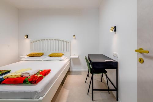 a white bedroom with a bed and a desk at 7 Olives Luxury Suites in Rogoznica
