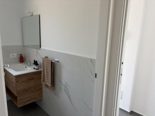 a white bathroom with a sink and a mirror at Attico Terracotta in Borgo Bainsizza