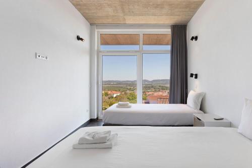 two beds in a room with a large window at Colina do Sol 1 in Amoreira