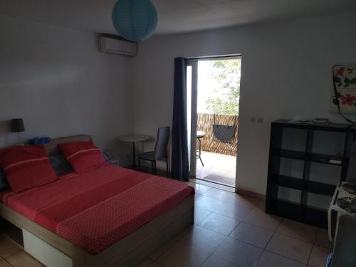 a bedroom with a bed and a door to a patio at Studio Les Avirons centre ville in Les Avirons