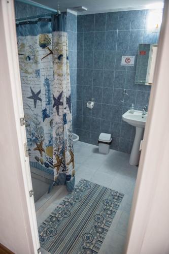 a bathroom with a shower curtain and a sink at Casa Albă in Sănduleşti