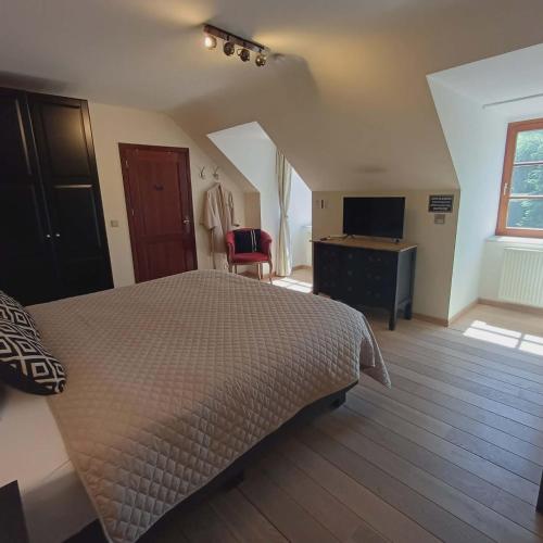 a bedroom with a bed and a desk and a television at B&B Madoli in Érezée
