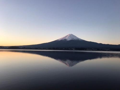 a mountain reflection in a lake with a mountain in the background at West Inn Fuji-Yoshida in Fujiyoshida