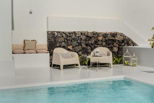 a pool with chairs and a table next to a stone wall at Villa Lore by Villalize in Teguise