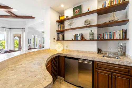 a kitchen with a large counter with a sink and shelves at Palmilla Golf and Beach Villa in San José del Cabo