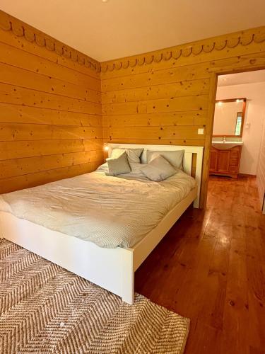 a bed in a room with a wooden wall at Duplex familial à la campagne in Orcier
