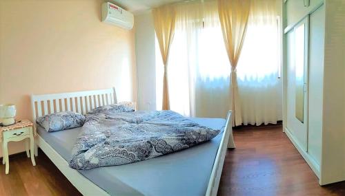 a bed in a bedroom with a large window at Ilidza Holiday Home in Sarajevo
