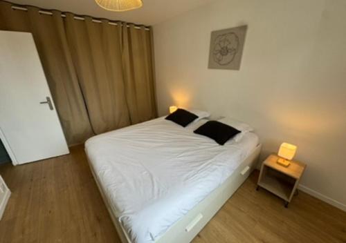 a bedroom with a bed with white sheets and black pillows at T2 Calme et Moderne in Margny-lès-Compiègne