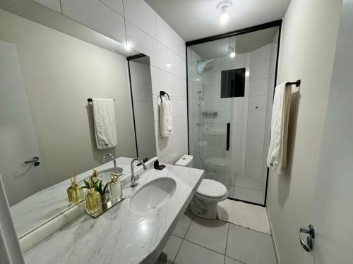a white bathroom with a sink and a toilet at Apartamento 2 quartos e 2 camas casal in Cascavel