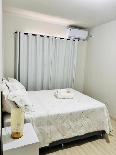a bedroom with a bed with a white blanket at Apartamento 2 quartos e 2 camas casal in Cascavel