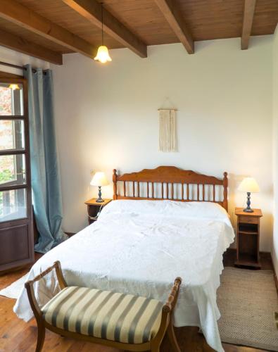 a bedroom with a large white bed with a bench at Casa del Sur El Collau in Porrúa