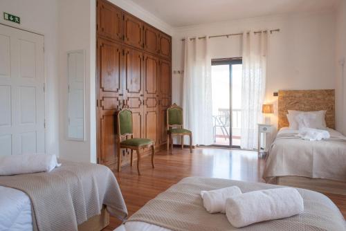a white room with two beds and a window at Estoril Guest Palace in Estoril