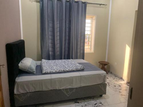 a bedroom with a bed with a blue curtain at KATEL Green appartements in Kolwezi