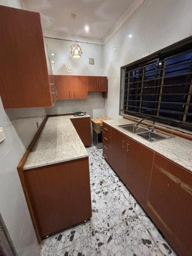 an empty kitchen with wooden cabinets and a sink at KATEL Green appartements in Kolwezi