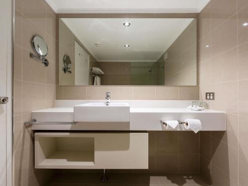 a bathroom with a sink and a mirror at Mercure Canberra in Canberra