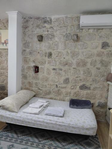 a bed in a room with a stone wall at Agica apartment in Škaljari