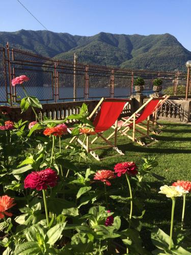 two chairs and flowers with mountains in the background at Villa Albonico in Laglio