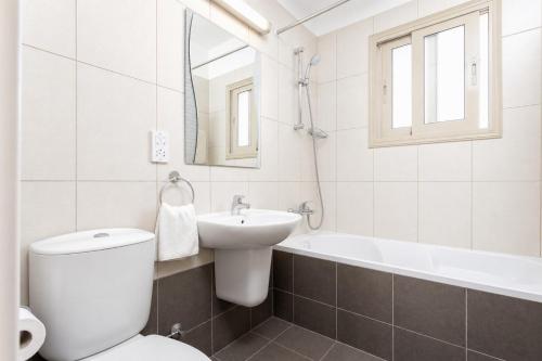 a bathroom with a toilet and a sink and a tub at Villa Panorama Tessera in Drousha