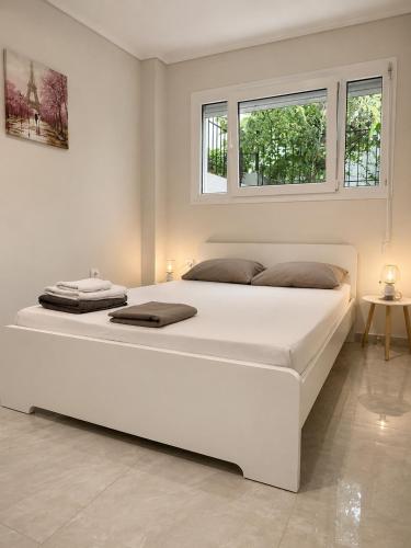 a large white bed in a white room with two windows at Xsoma Flats "Studio" in Thessaloniki