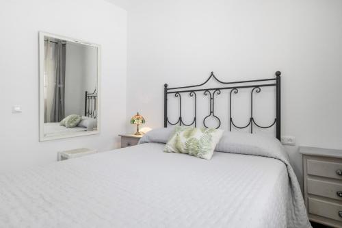a bedroom with a white bed with a black headboard at Playa de Conil in Conil de la Frontera