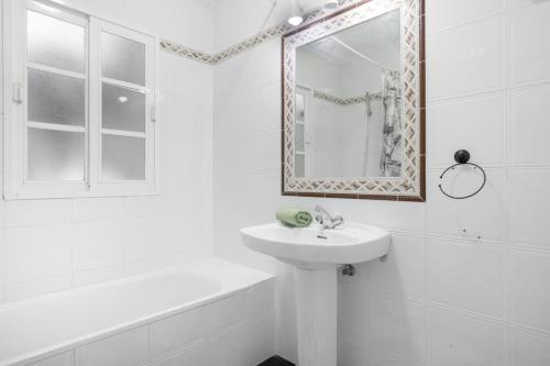a white bathroom with a sink and a mirror at Playa de Conil in Conil de la Frontera