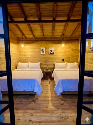 two beds in a room with wooden walls at Villa Colombia in Vianí