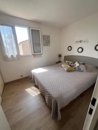 a bedroom with a large bed and two windows at Maisonnette les Marines d'Helios T2 cabine in Marseillan