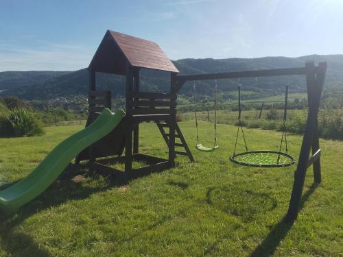 a playground with a slide and swings in a field at ORLIK - pokoje gościnne in Uście Gorlickie