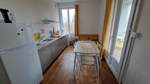 a small kitchen with a table and a refrigerator at Les Tournesols in Égletons