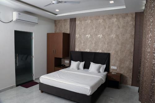 a bedroom with a large bed with white sheets at Hotel Maurya Greens in Banbāsa