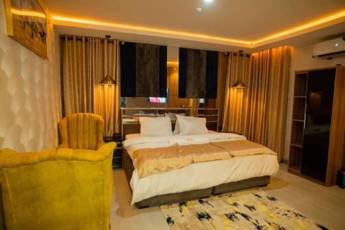 a bedroom with a large bed and a chair at Trev Hotels and Suites in Asaba