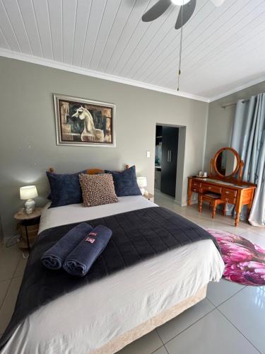 a bedroom with a large bed with blue pillows on it at Peace Lily Garden Cottage in George
