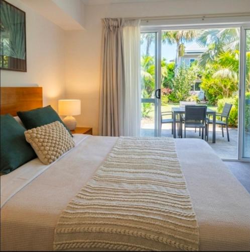 a bedroom with a bed and a patio with a table at Cozy water side apartment - Jetty in Mandurah
