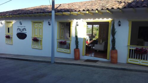 a white house with yellow doors and windows at Hotel Salento Plaza in Salento