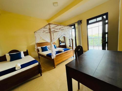 a bedroom with two beds and a table in it at Nature's Crest Resort in Urulewatta