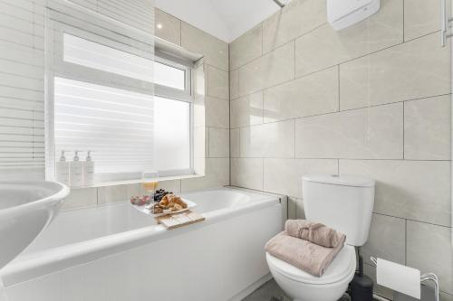 a white bathroom with a tub and a toilet and a sink at Modern House, Pool Table, Parking & Garden in Fallings Park