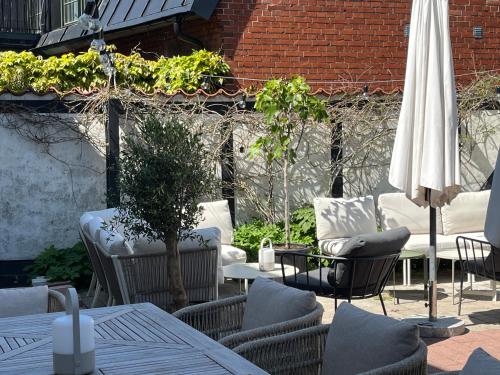 a patio with tables and chairs and a white umbrella at Hotell Bäckagården in Ystad