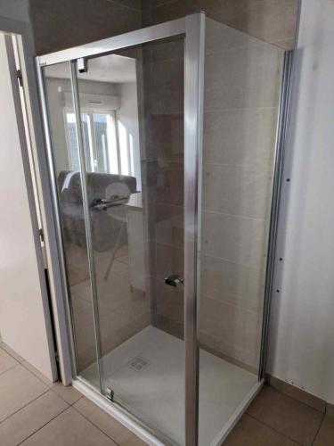 a glass shower door in a room with at Jolie maison proche commodités, idéal vacances ou professionnels in Pleyben