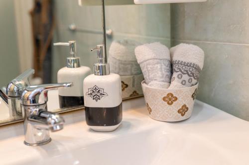 a bathroom sink with two bottles of soap and towels at By Domy 2 Grottaglie in Grottaglie