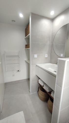 a white bathroom with a sink and a mirror at La petite maison de la Drôme in Aouste-sur-Sye